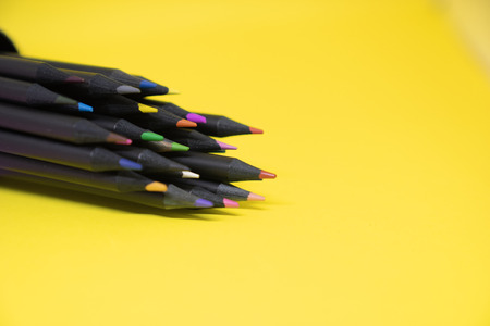 selective focus of group of black colourful pencil on yellow background with copy spaceの写真素材