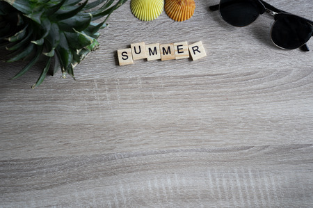 flat lay top view summer word written on wooden block with sunglasses, seashell and head of pine...