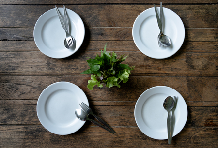4 Empty plates and stanless spoon and fork on dark wooden background. Top view with copy space