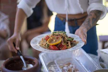 close upa woman hand with tattoo holding papaya salad, Som Tum when is prepared