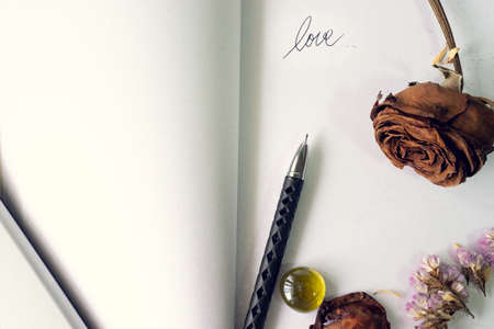 top view flat layer witerd old rusty brown roses, dried lavender flowers, pen and love word  on blank white book , love forever, memory conceptの写真素材