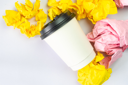 white coffee cup with colourful crumbled paper balls on white backgroundの写真素材