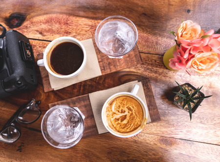 top view black coffee and milk coffee  in white ceramic cup on wooden background with flower and...