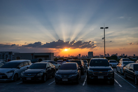 The sun is setting on twilight dramatic sky, over cars, on top roof carpark in Bangkok. Thailand. 27/10/18のeditorial素材