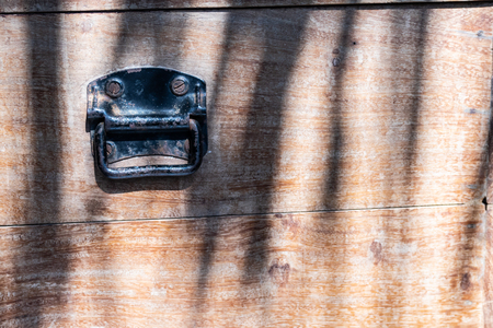 close up black rusty  vintage metal handle on wooden box background with light and shadowの写真素材