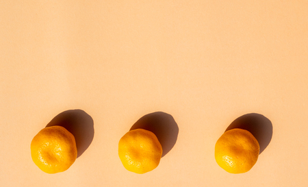 3 whole oranges with strong shadow on orange background, copy spaceの写真素材