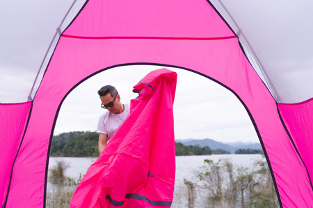 an asian man setting pink tent at campgroundの写真素材