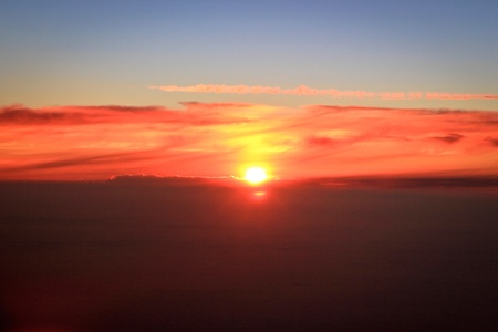 An orange sun rising over the cloudsの写真素材