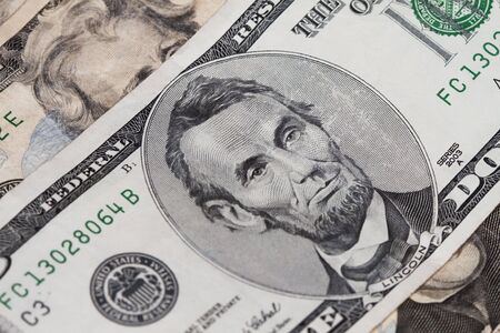 Abraham lincoln in the five dollar bill with two twenties out of focus above and below.