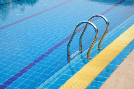 Grab bars ladder in the blue swimming pool