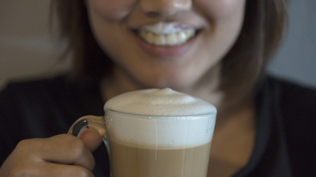 Asian girl with white fpam of cappuccino on her lipの写真素材