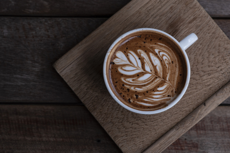 Nice shape of latte art coffee serve on wooden plateの写真素材