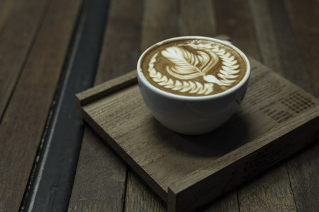 Nice shape of latte art coffee serve on wooden plateの写真素材