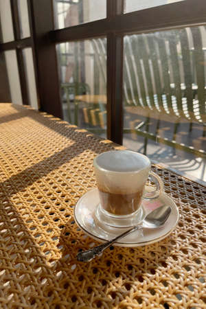 Hard latte coffee shot serve in small shot glass against sunlight from window shade in vintage cafeの写真素材