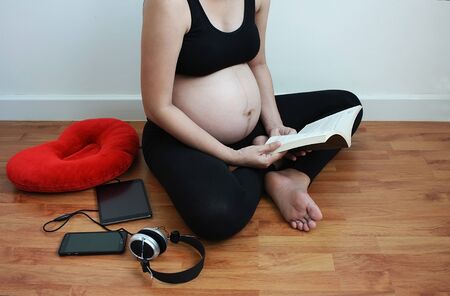 pregnant asian women reading a book in free time, sometime she playing tablet or listen to music for...