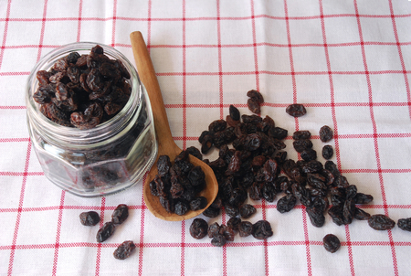 raisin in a glass container and ladle wood decorate on plaid napkinの写真素材
