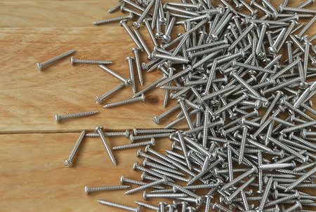 A lot of metal sharp screws are placed on a wooden background.の写真素材