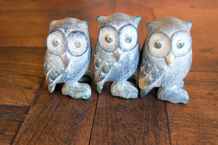 Three small owl statue. Decoration on brown wood floor. Look like a friendship or teamwork concept.の写真素材