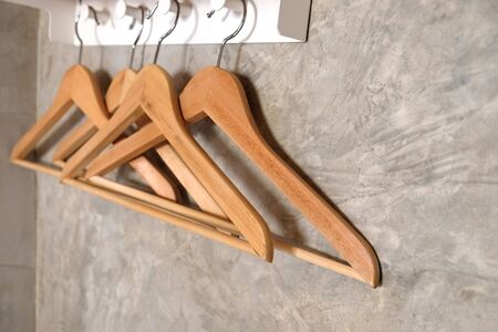 The hanger is made of brown wood, it hangs on the gray cement wall.の写真素材