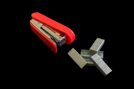 Red stapler and staples steel isolated on black backgroundの写真素材