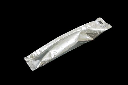 Packaging aluminum foil coffee stick pouch isolated on blackの写真素材