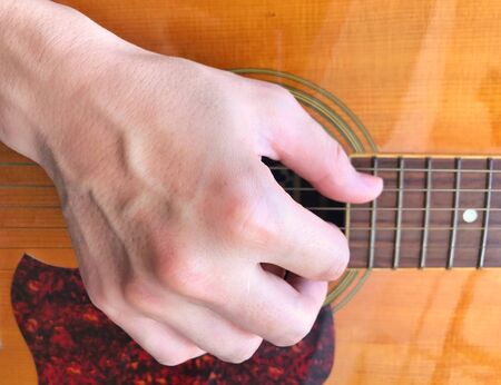 Closeup the man playing on acoustic guitar