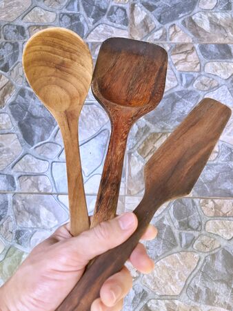 Hand holding wooden ladle and spatulaの写真素材