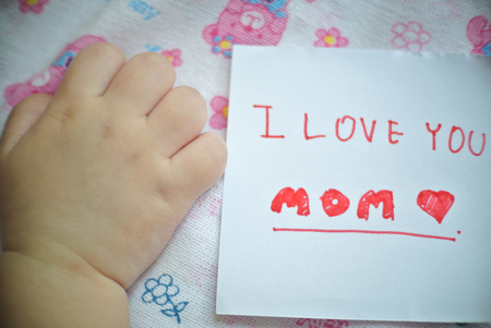 Happy mothers day. I love you mom. Thank you mom. with little baby hand and love stoneの写真素材