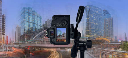 DSLR camera on tripod shooting modern building at twilight. Traffic in the busy business districtの写真素材