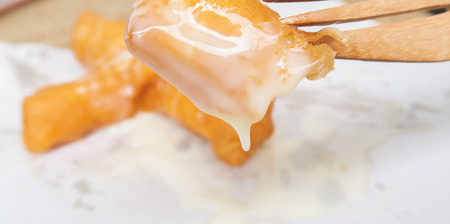 taking  deep fried dough stick with condensed milk topping  fork