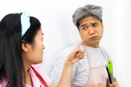 Angry woman pointing her finger against her husband on white background..housework concept.の写真素材