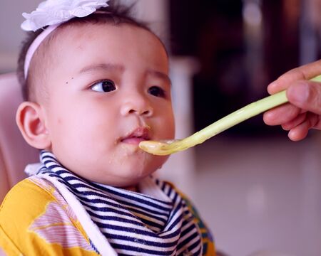 Infant girls eating mashed potatoes mixed with water