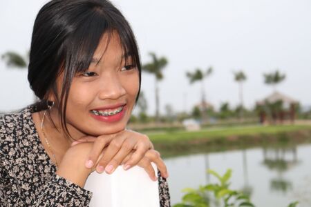 A beautiful young lady smiles in a summer flower garden in Thailand.の写真素材