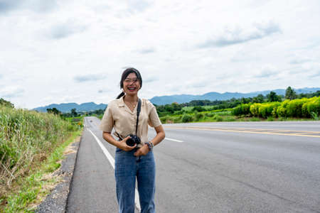 A long-haired woman carrying a smiling camera on a paved road, beautiful nature background mountain view in Dan Khun Thot District, Nakhon Ratchasima Province, Thailand, on September 7, 2020.のeditorial素材