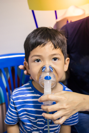 Asian little boy making inhalation with nebulizer blurの写真素材