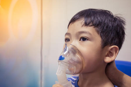 Asian little boy making inhalation with nebulizer blurの写真素材