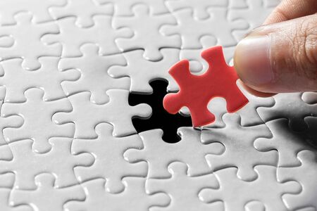 Hand holding piece of blank jigsaw puzzle detail blur