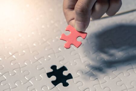 Hand holding piece of blank jigsaw puzzle detail blur