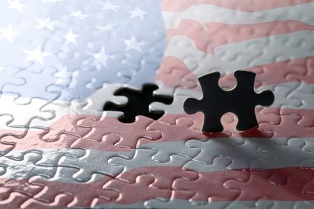 Jigsaw puzzle piece black silhouette. On the background is a united states flag jigsaw puzzle  detail blurの写真素材