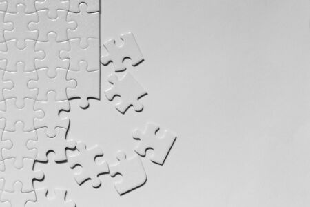 Closeup jigsaw puzzle white piece on white backdropの写真素材