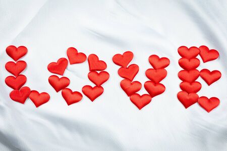 Many red hearts print the word love on a wrinkled white background detail object art