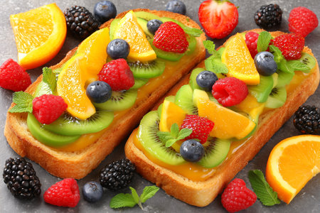 Delight in a fresh avocado toast topped with a variety of colorful fruits, complemented by a smoothie bowl. A vibrant and healthy breakfast choice thatの素材