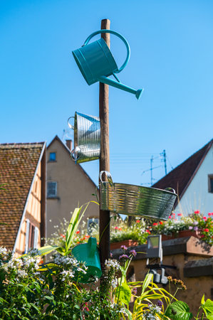 Hands watering plants with a metal bucket hanging on a logの写真素材