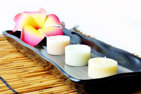 Three candles and plumeria in plate on bamboo matの写真素材