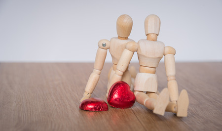 A couple of wooden doll man on valentine days showing love to each other and focus either on heart-shaped chocolate and the coupleの写真素材