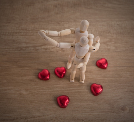 A couple of wooden doll man on valentine days showing love to each other and focus either on heart-shaped chocolate and the coupleの写真素材