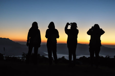 Happy men silhouette sunrise on the mountainの写真素材