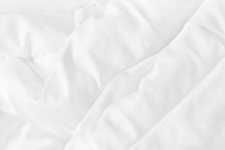 Close up top view of white bedding sheet and wrinkle messy blanket in bedroom after wake up in the...