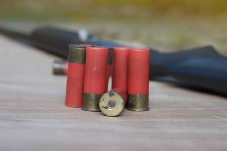 Close-up of ammo and shotgun on wood floor with selective focus.の写真素材