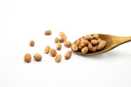 Peanuts in a wooden spoon And some are scattered  isolated on a white background